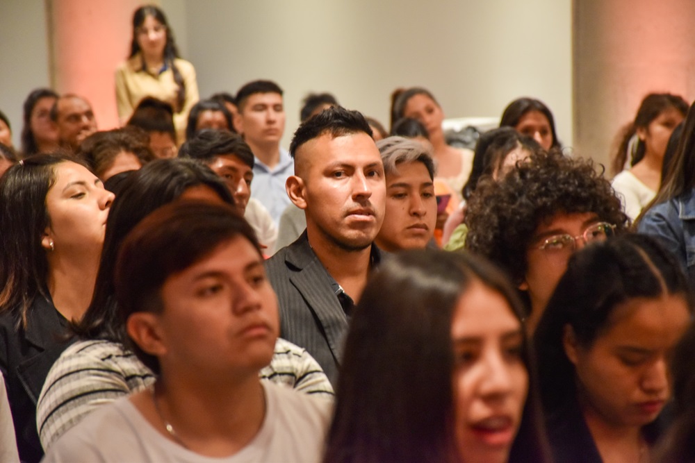 Jóvnes y personas adultas sentadas en un auditorio.