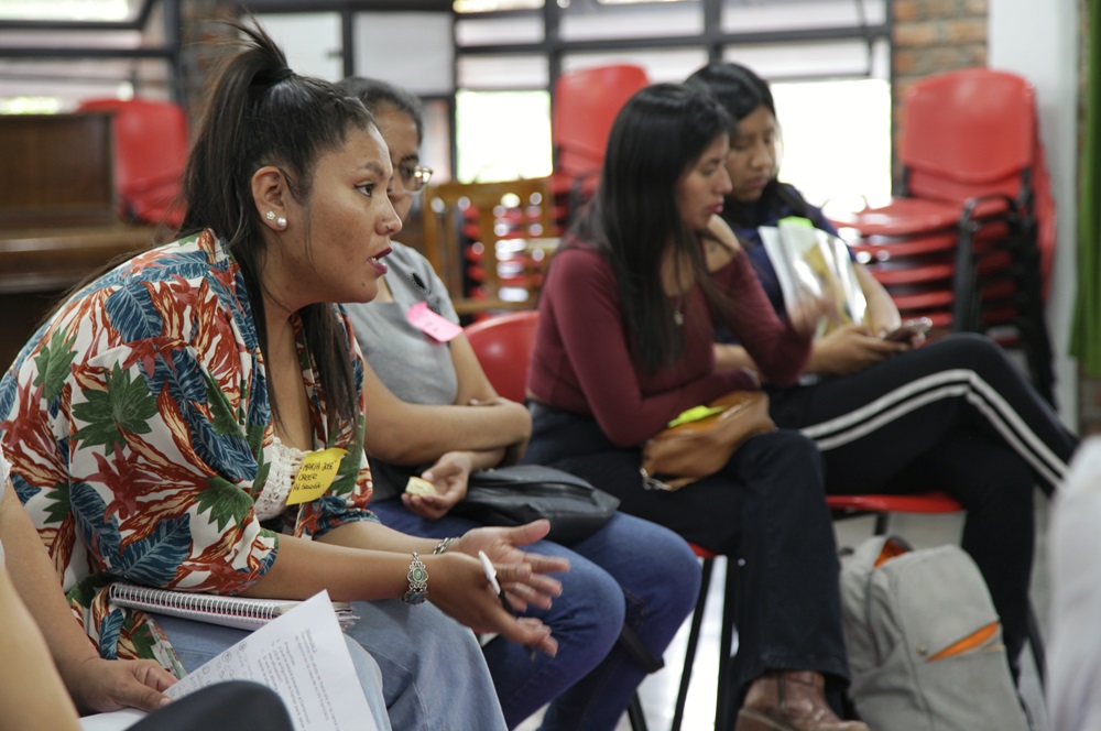 Cuatro mujeres jóvenes sentadas en sillas y escuchando en el taller