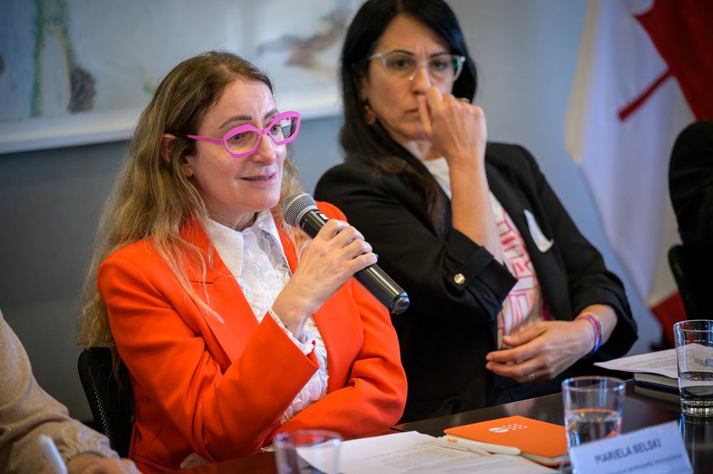 Mariela Belski, de pelo largo y lentes, habla con micrófono ante la gente