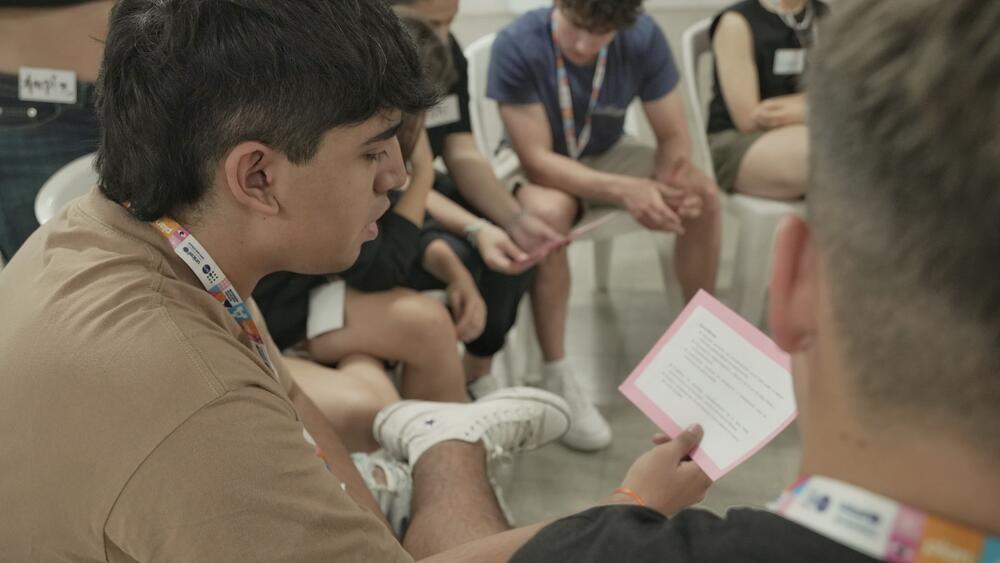 Jóvenenes conversan sobre uno de los ejes centrales de Plan A. Uno de ellos sostiene un papel y lee, mientras el resto escucha