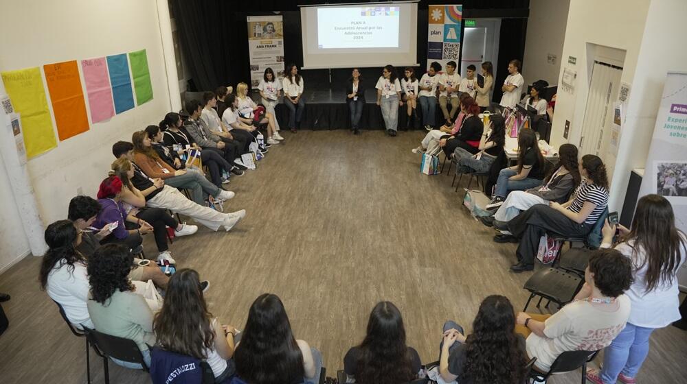 Jóvenes y personas adultas sentadas en ronda en el taller de Plan A