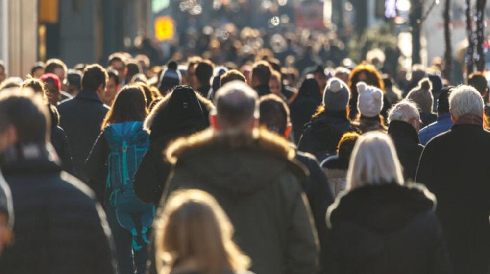 Decenas de personas caminando por una calle. 