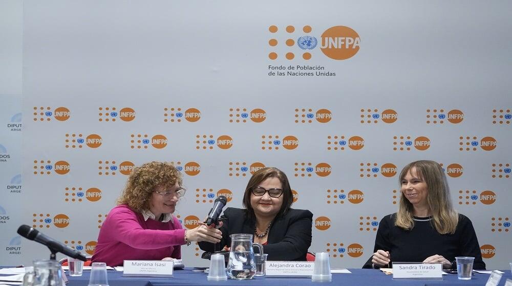 Tres mujeres, representantes de UNFPA y del gobierno de Argentina. De fondo, un panel con logo UNFPA