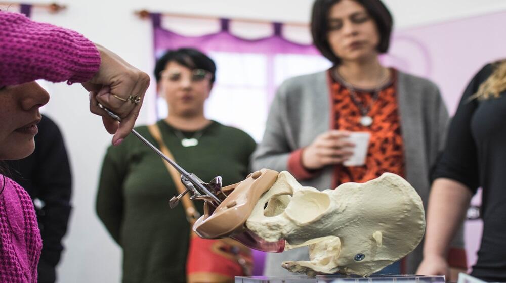 Una mujer muestra a otras personas cómo se coloca un método anticonceptivo