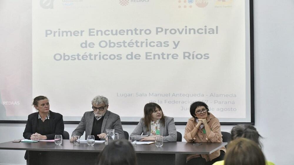 Tres mujeres y un hombre sentados detrás de una mesa.  Detrás de las personas hay una pantalla donde se proyecta la frase "Prime